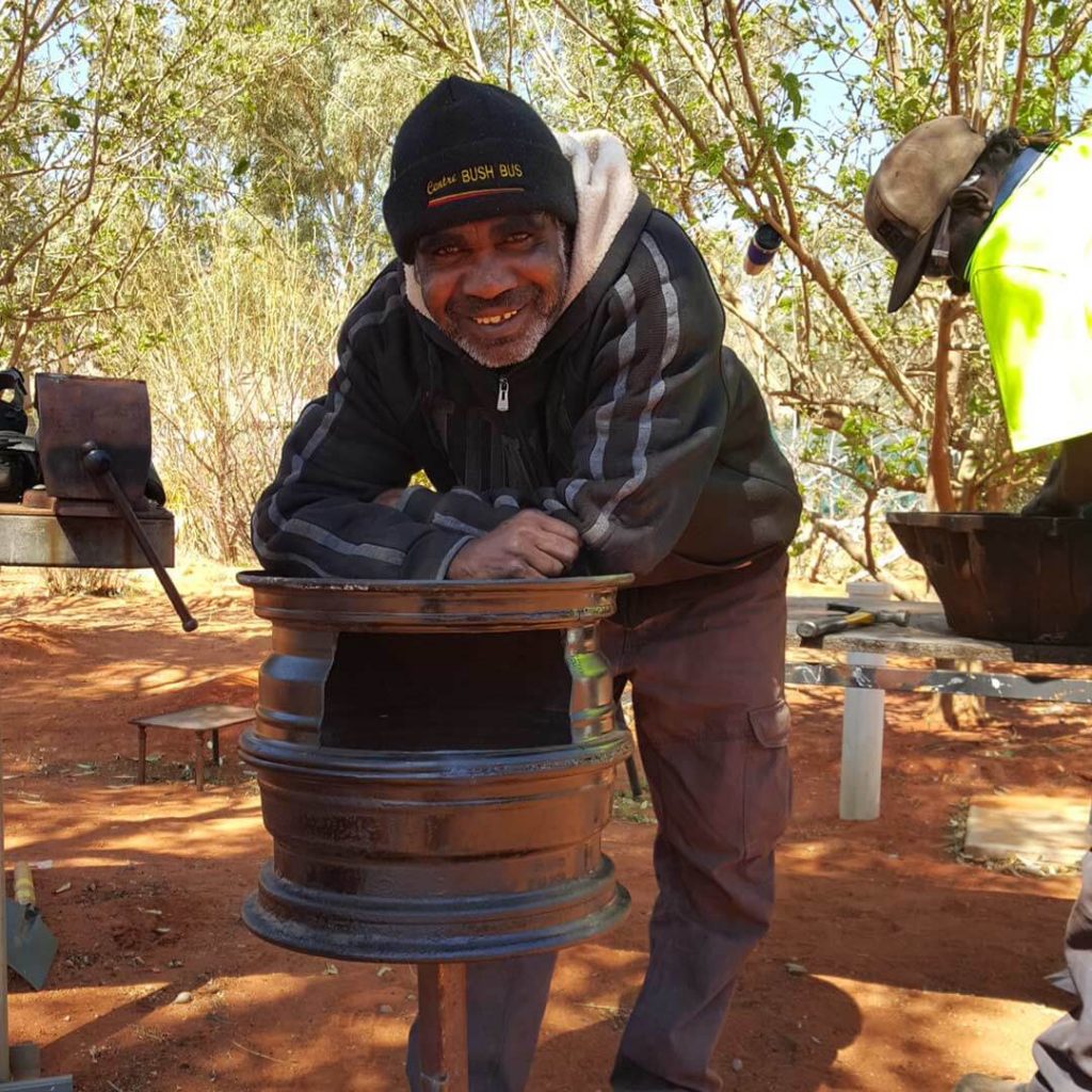 Image: Man wearing a beanie and smiling while working in community